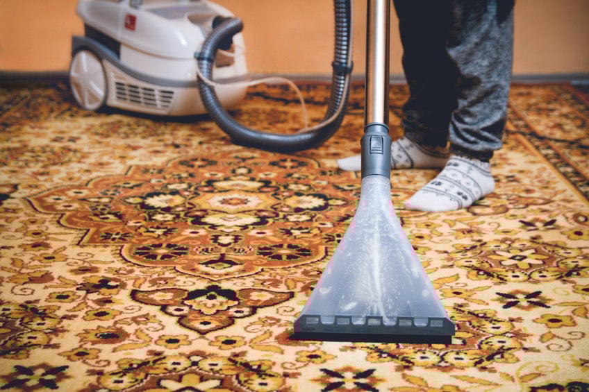 Woman cleaning persian carpet by washing hoover